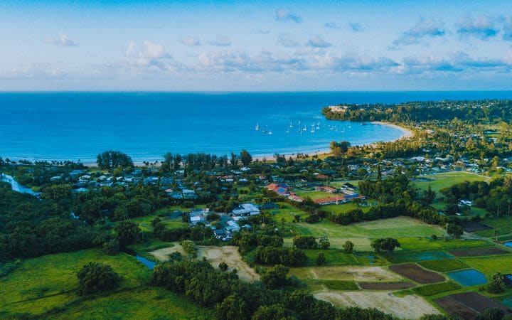 Aerial view of Hanalei town and its taro fields beside a wide blue bay
