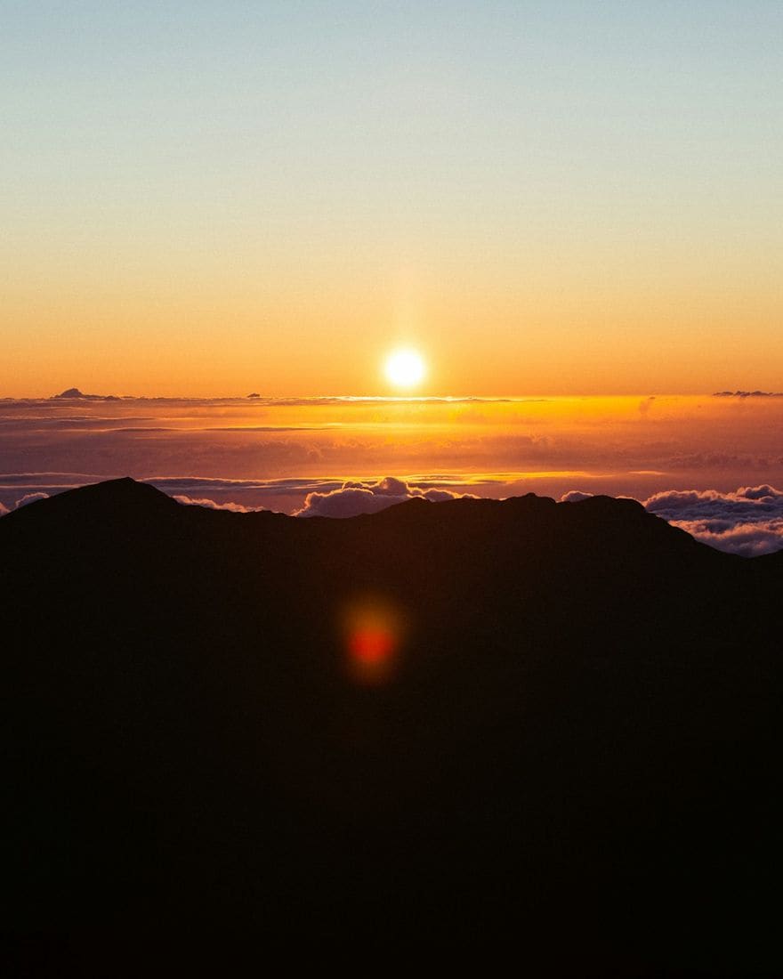 The sun rising over a sea of clouds, seen from the summit of Haleakalā