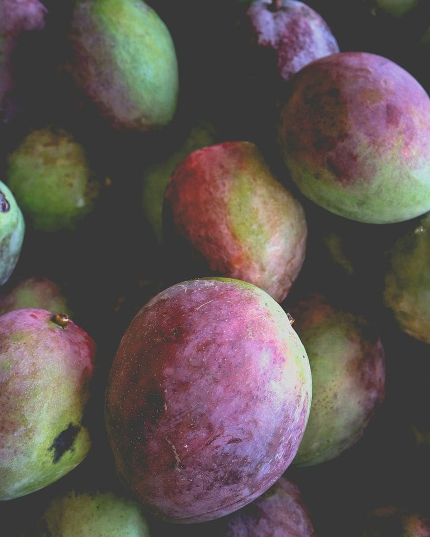 A pile of ripe red and green mangoes at a market stall