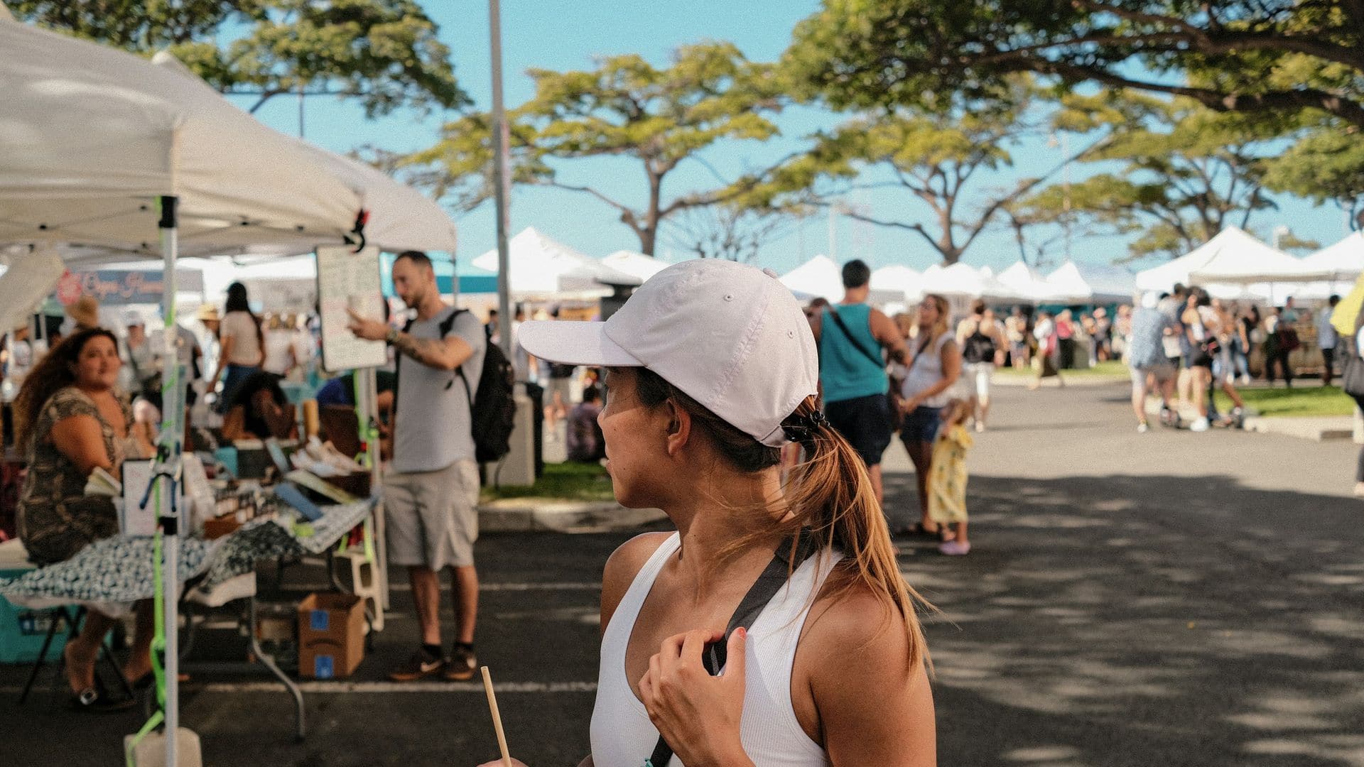 Shoppers browsing stalls under white tents at a Honolulu farmers market